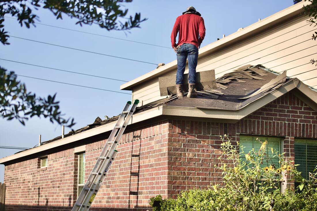 a construction worker on a house roof doing roofing